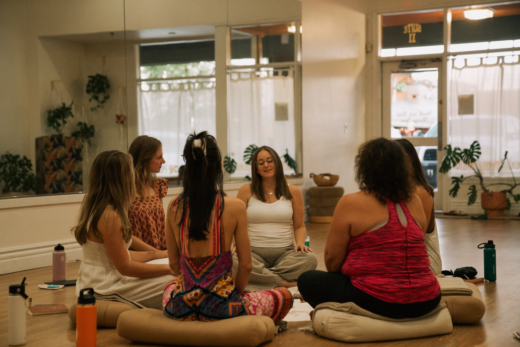 Women meditating together on cushions in a bright studio