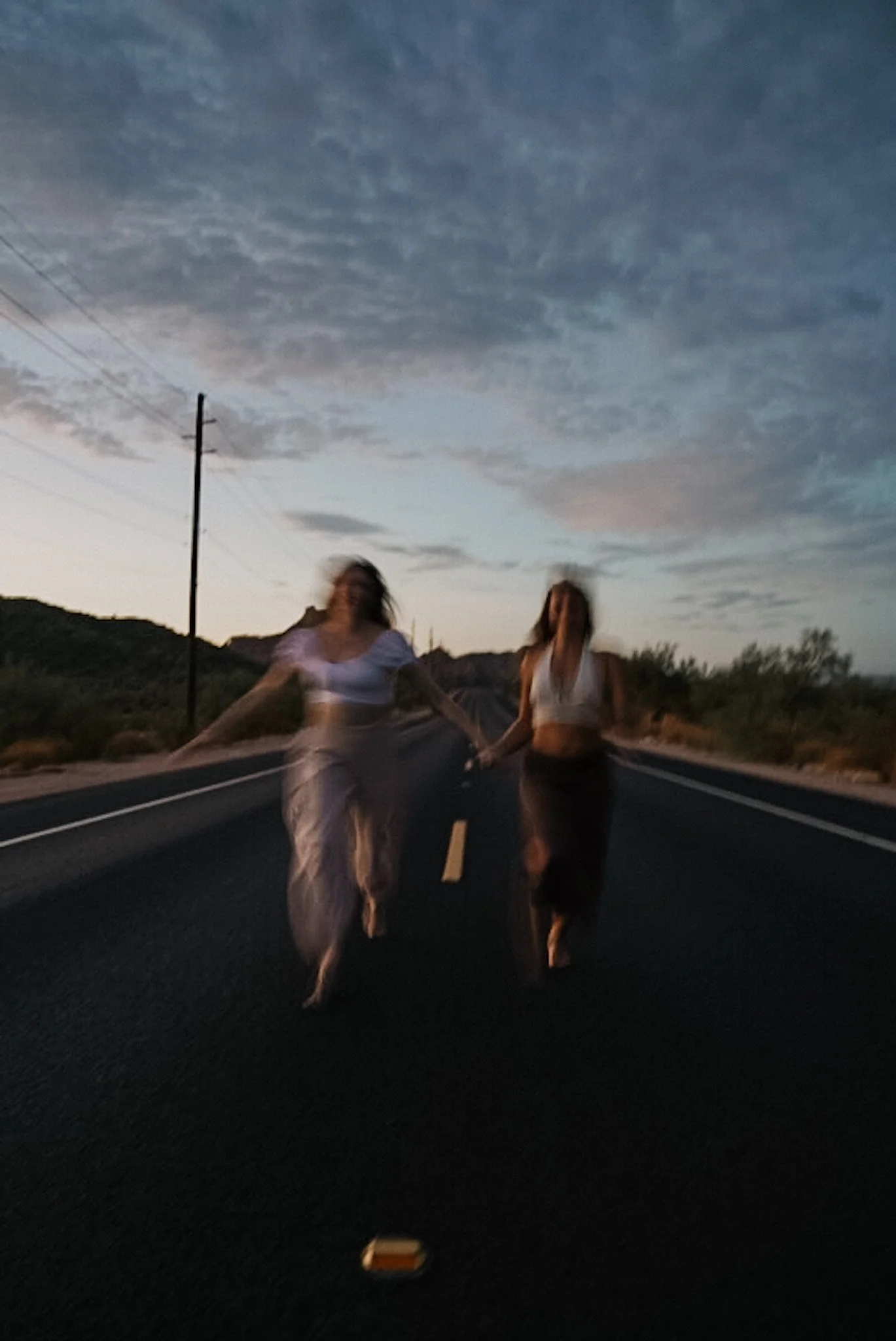 Two women walking a desert road at dusk